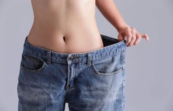 Slim woman after weight loss surgery in her old much too big jeans.