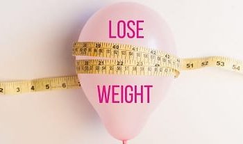 A pink ballon with sign that reads lose weight wrapped with a measuring tape.