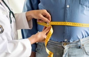 A doctor measuring waist of an overweight man.