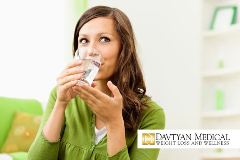 Cheerful woman drinking water out of glass.