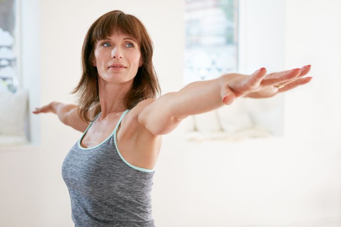 Mature woman wearing fitness outfit stretching her arms.