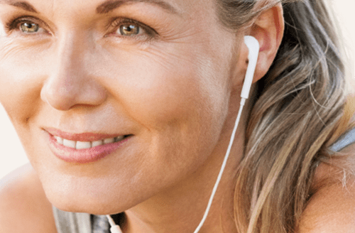 A satisfied athletic middle-aged woman listening to music while doing sport.