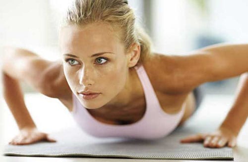 A fit woman doing pushups on a sports mat.
