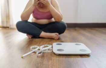 Obese Woman with fat upset bored of dieting Weight loss fail  Fat diet and scale sad asian woman on weight scale at home weight control.